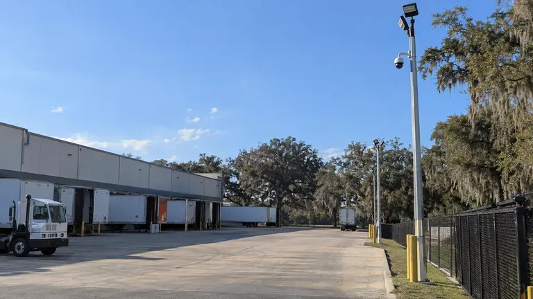 Truck yard with loading docks, parked trailers and pole-mounted cameras covering separate operating zones