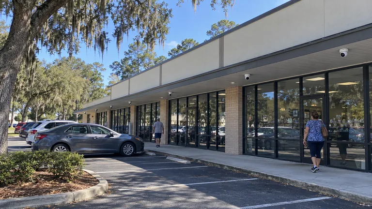 Ocala retail strip center with cameras mounted under the storefront canopy and a shared parking lot