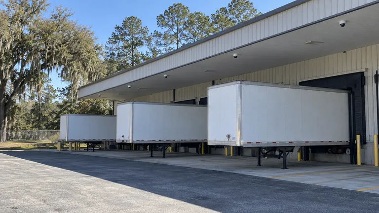 Single-story Ocala distribution warehouse with loading docks, trailers and cameras mounted under the dock canopy