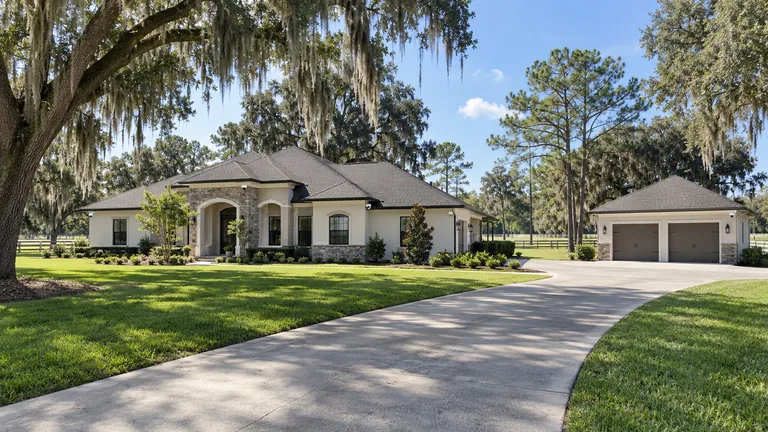 Estate home on acreage with dome cameras mounted flush under the eaves and at the detached garage